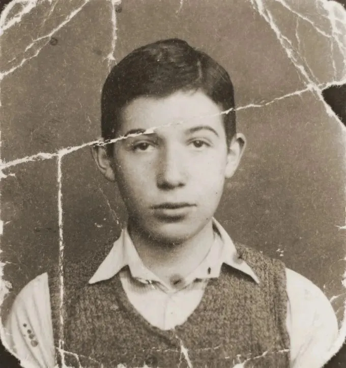 A boy in a knitted vest, the print broken by deep cracks across his face