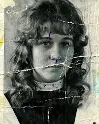 A young woman with curly hair, the print split by a lattice of cracks across her face