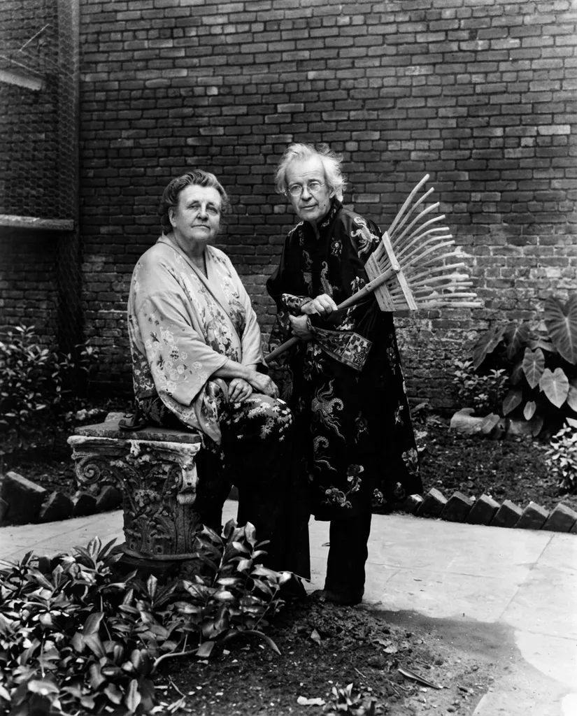The same garden portrait after restoration — dust and speckling removed, the brick wall and both robes' patterns clearer, the print cropped to the image itself